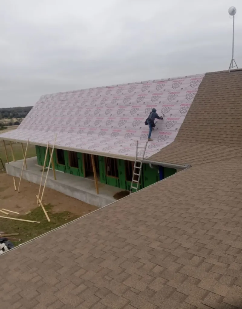 Worker preparing underlayment for a metal roof installation in Wausau